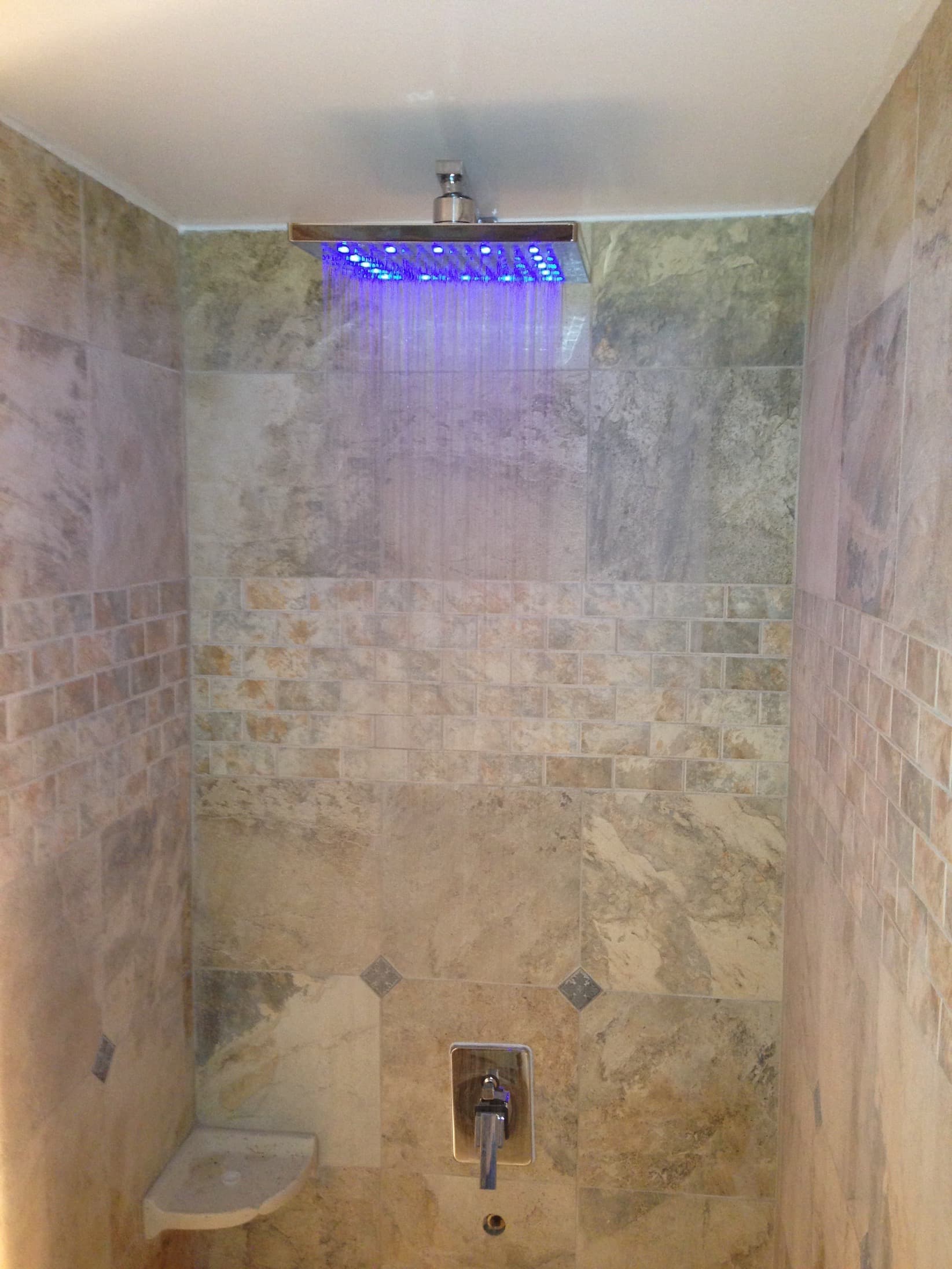 Custom travertine tile shower installation with LED rainfall showerhead in Maryland by Atlantic Construction