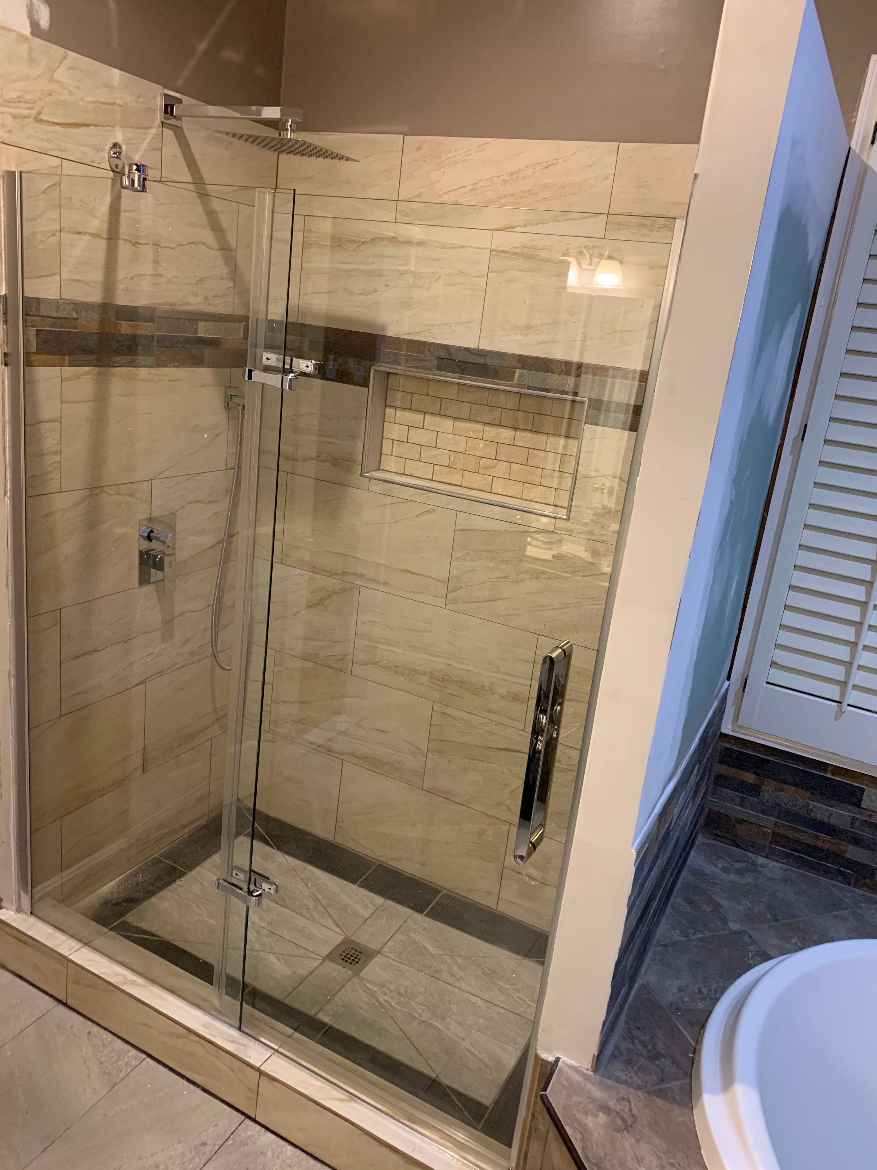 Luxury bathroom with marble tile shower and frameless glass door in Maryland by Atlantic Construction