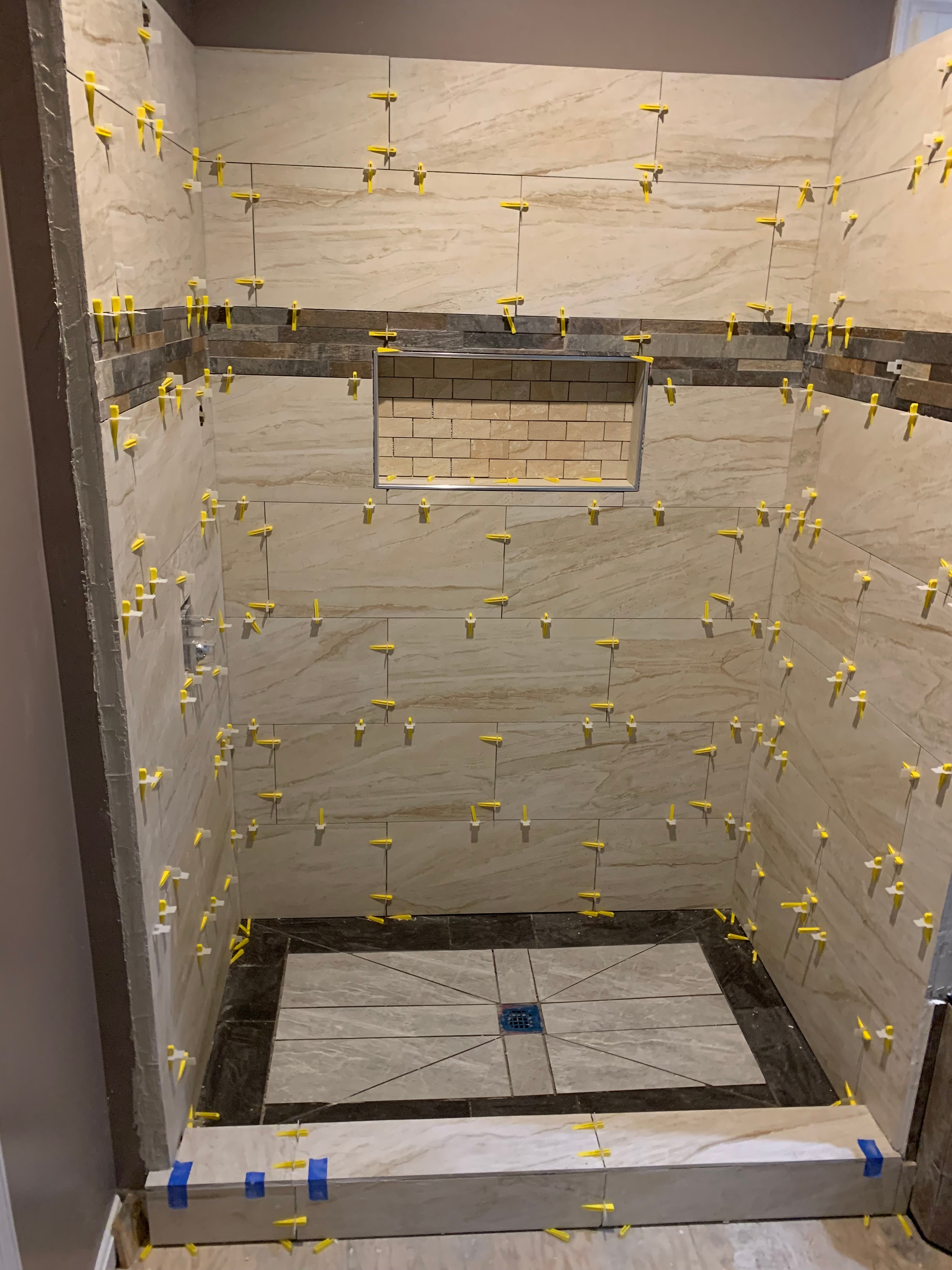 Luxury bathroom shower tile installation with marble and dark accent band in Maryland by Atlantic Construction